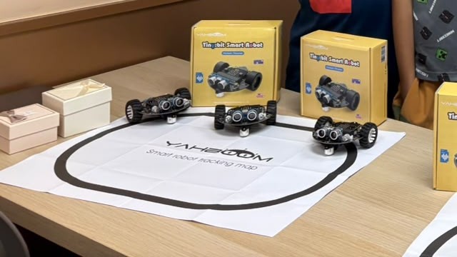 Robot cars the students built, lined up on the line-tracking map with their kits